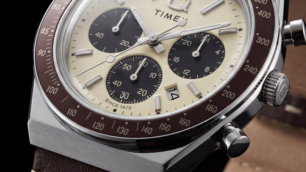 Close-up of the Q Timex Chronograph’s cream dial, black subdials, date window, and brown tachymeter bezel.