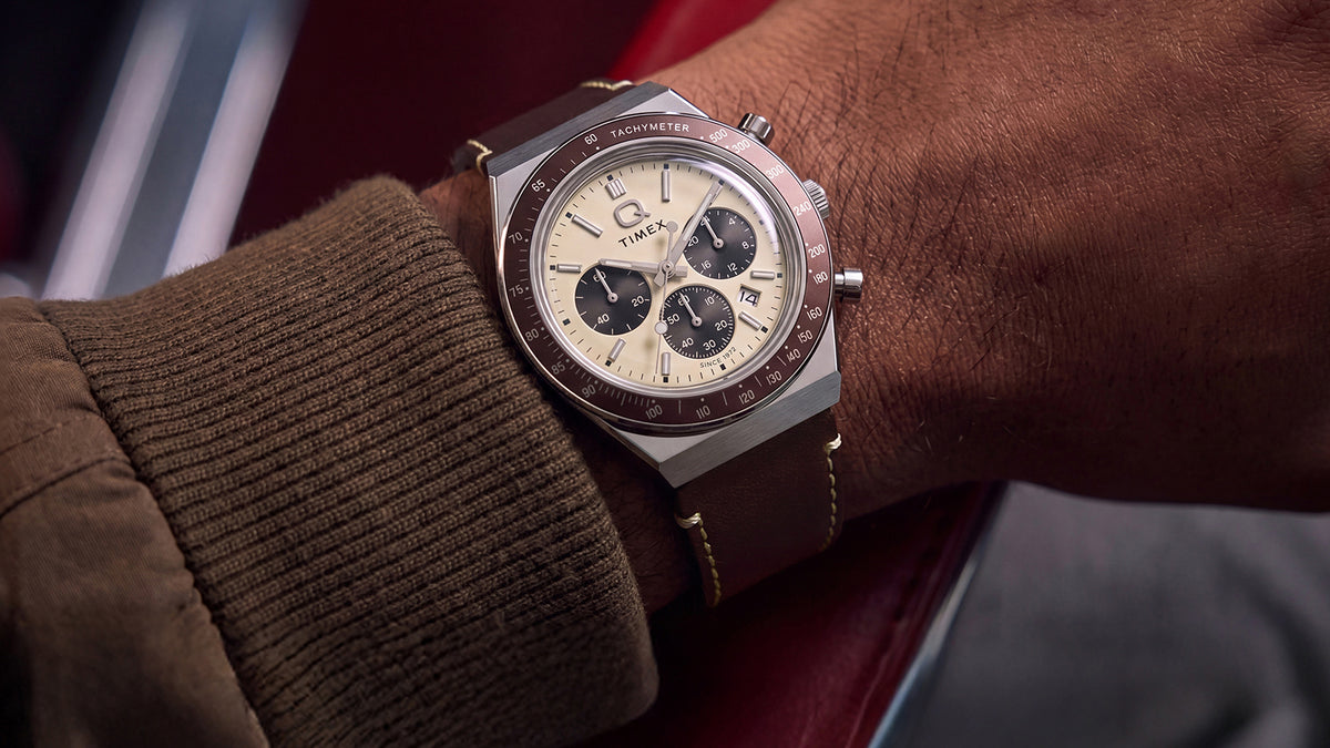 Q Timex Chronograph with a cream dial and brown leather strap worn on the wrist.