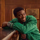 Person wearing the Waterbury Heritage Automatic GMT watch with a green jacket in a wood-paneled room.