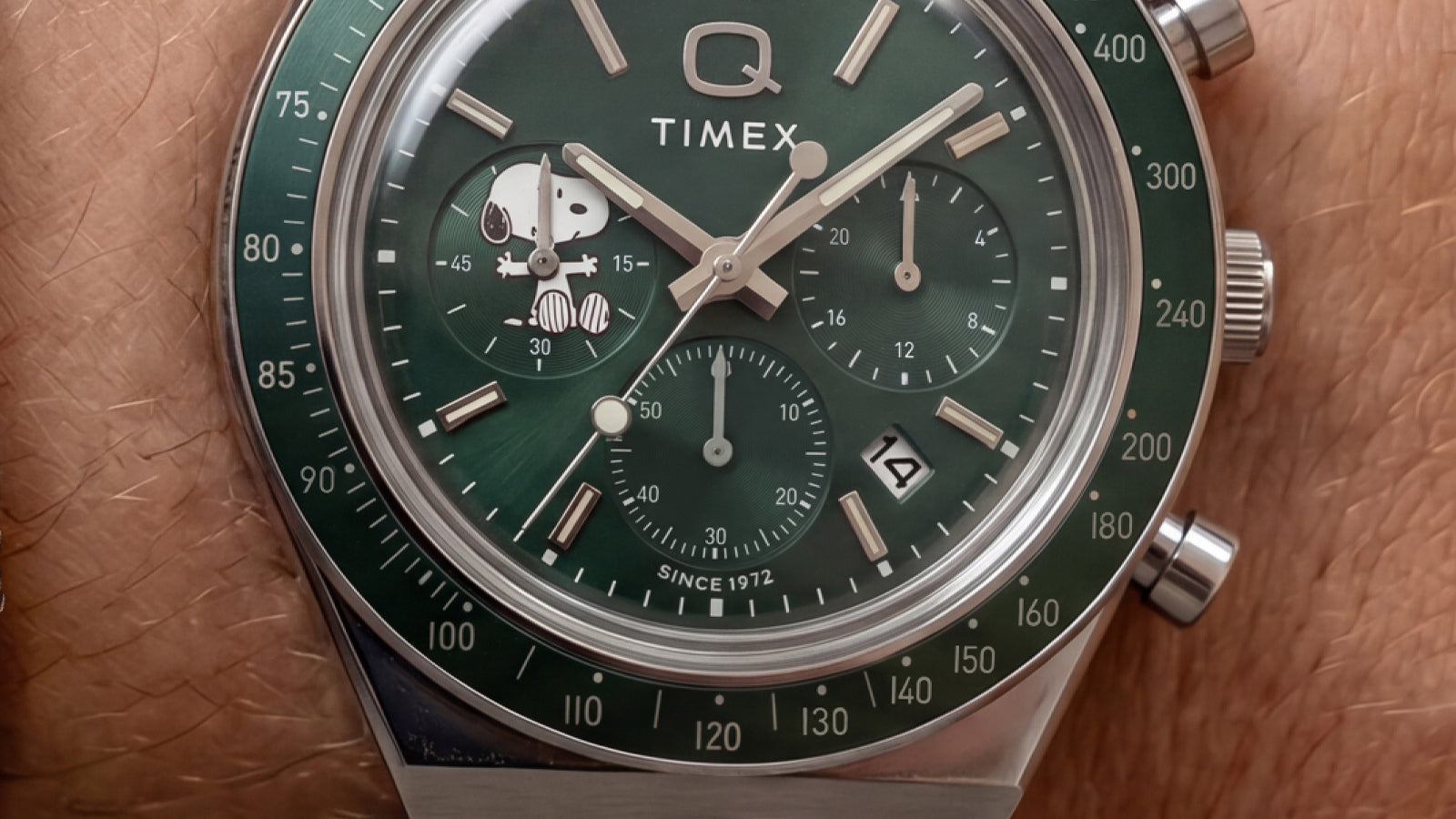 Primer plano de la esfera verde del cronógrafo, con Snoopy en una subesfera, índices plateados y una ventana de fecha.