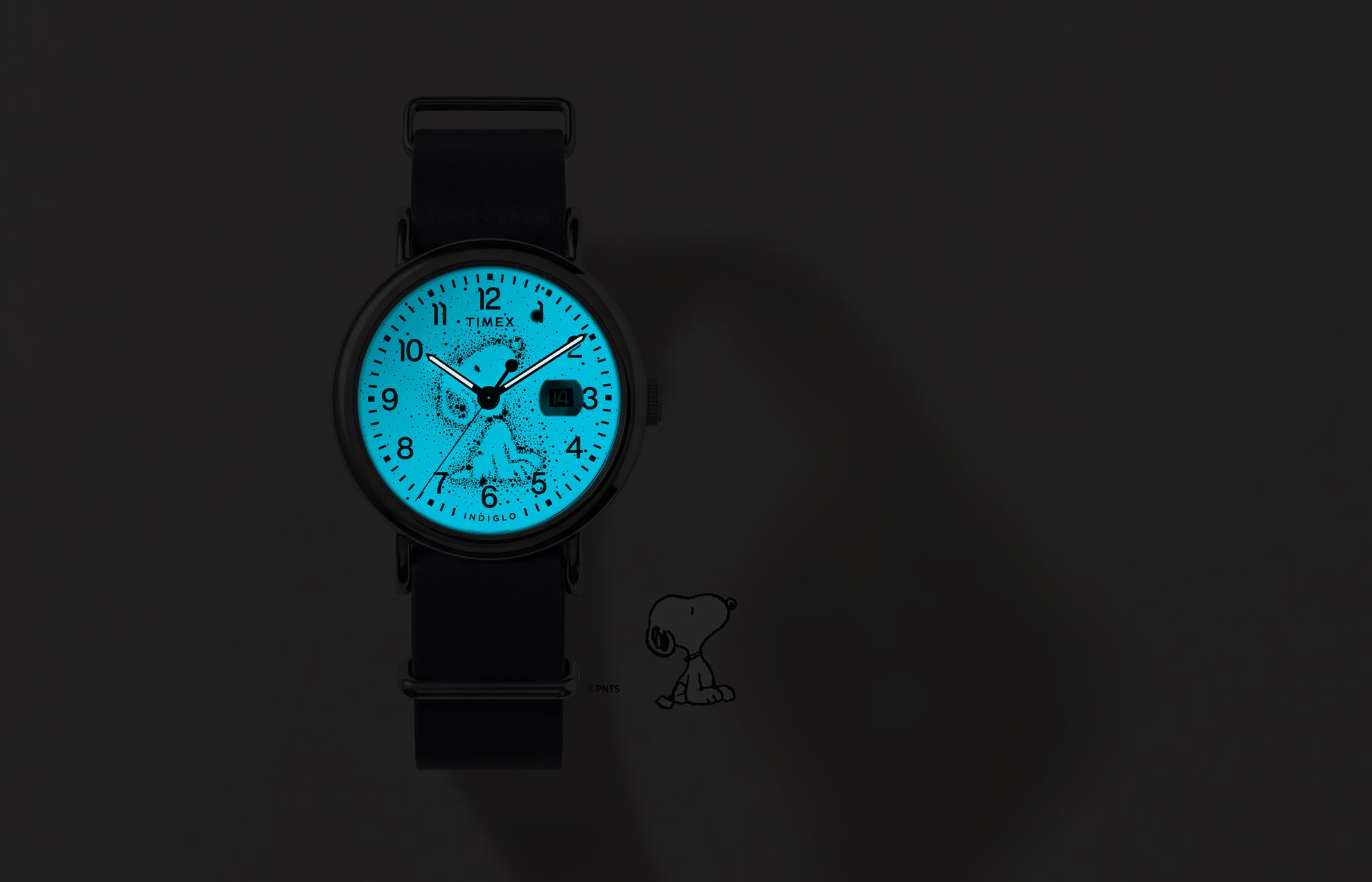 Reloj Peanuts® x Timex Weekender Astronomy fotografiado en la oscuridad, con su esfera azul INDIGLO® iluminando el diseño de la constelación de Snoopy.