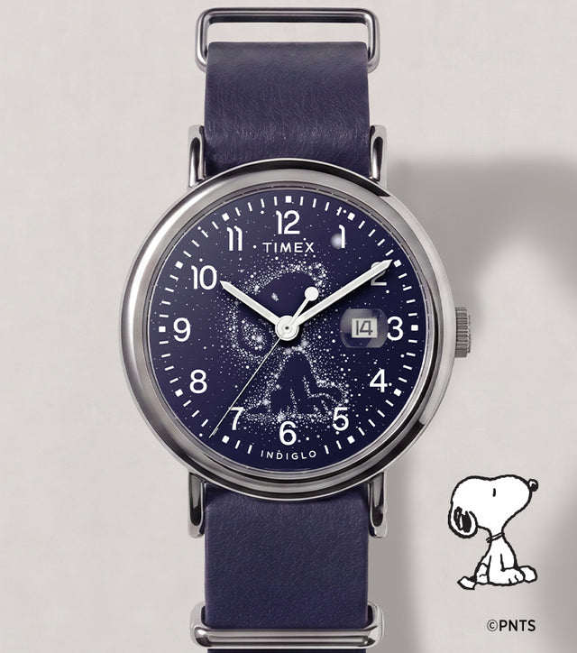 Reloj Peanuts® x Timex Weekender Astronomy con correa azul marino, caja en tono plateado, esfera con la constelación de Snoopy y ventana de fecha.