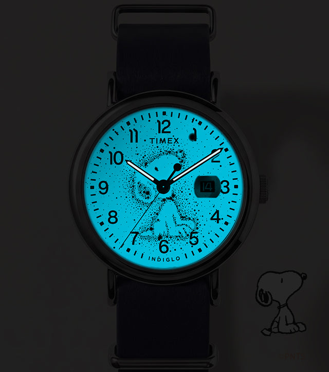 Reloj Peanuts® x Timex Weekender Astronomy fotografiado en la oscuridad, con su esfera azul INDIGLO® iluminando el diseño de la constelación de Snoopy.