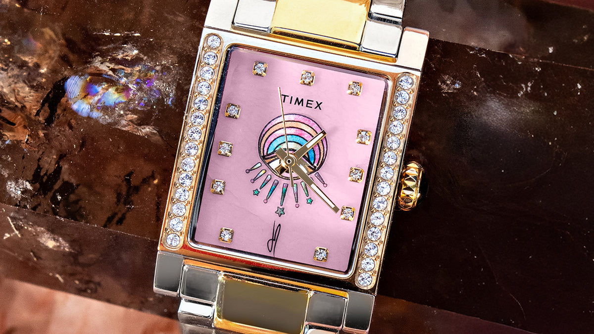Close-up of the Éclat watch’s pink eye-motif dial, crystal hour markers, and crystal-set rectangular case.