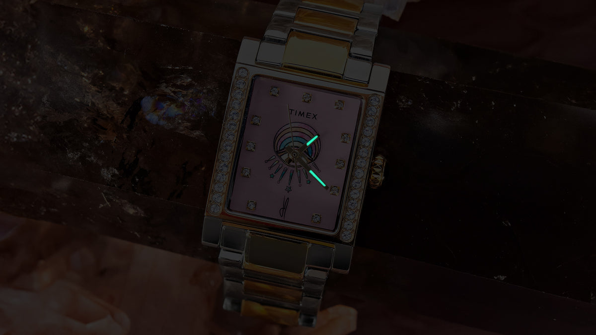 Close-up of the Timex x Jacquie Aiche Éclat watch in the dark with its hands glowing.