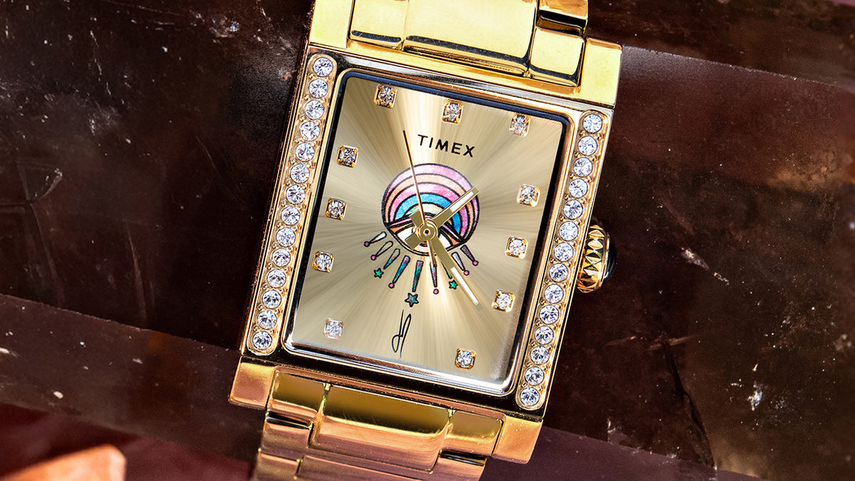 Close-up of the Éclat watch’s champagne eye-motif dial, crystal hour markers, and crystal-set rectangular case.