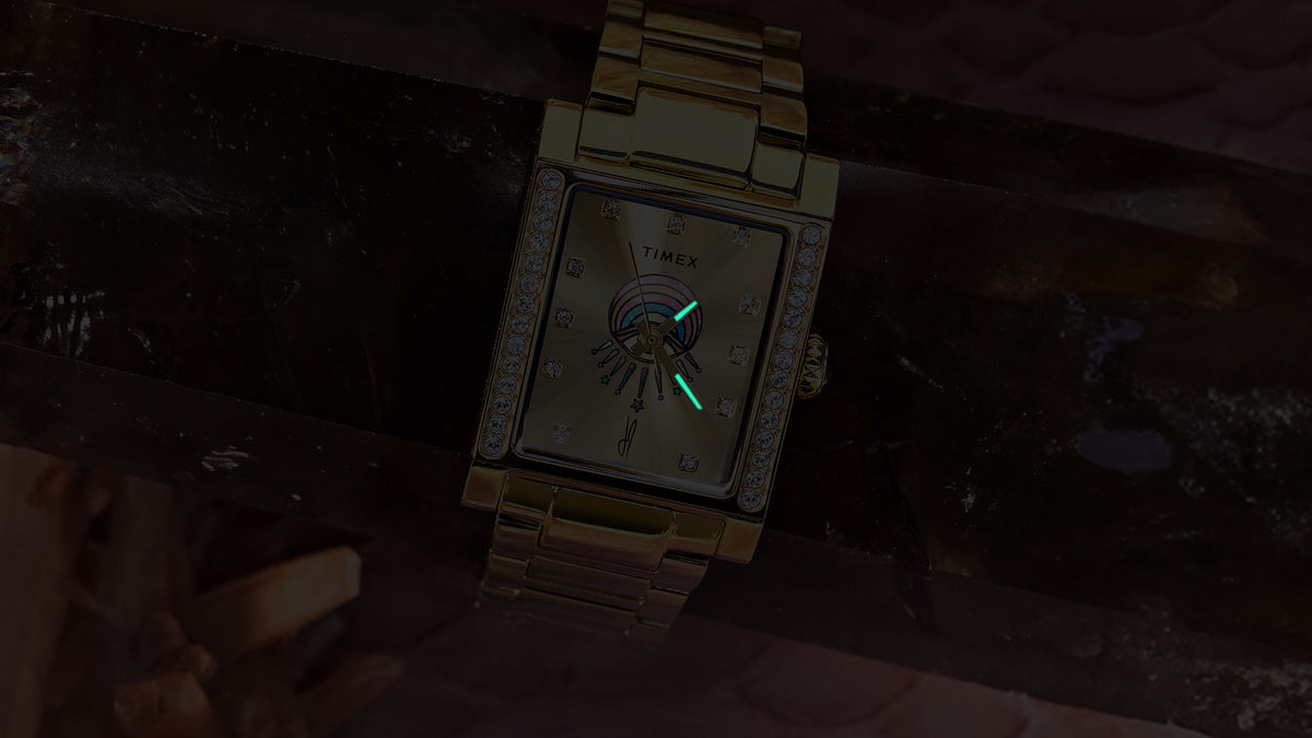 Close-up of the gold-tone Éclat watch in the dark with its hands glowing.