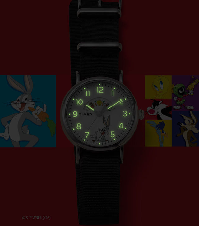 TW2Y99100 Looney Tunes Bugs and Friends x Timex Standard watch with glowing green hands and numerals beside Looney Tunes character artwork.