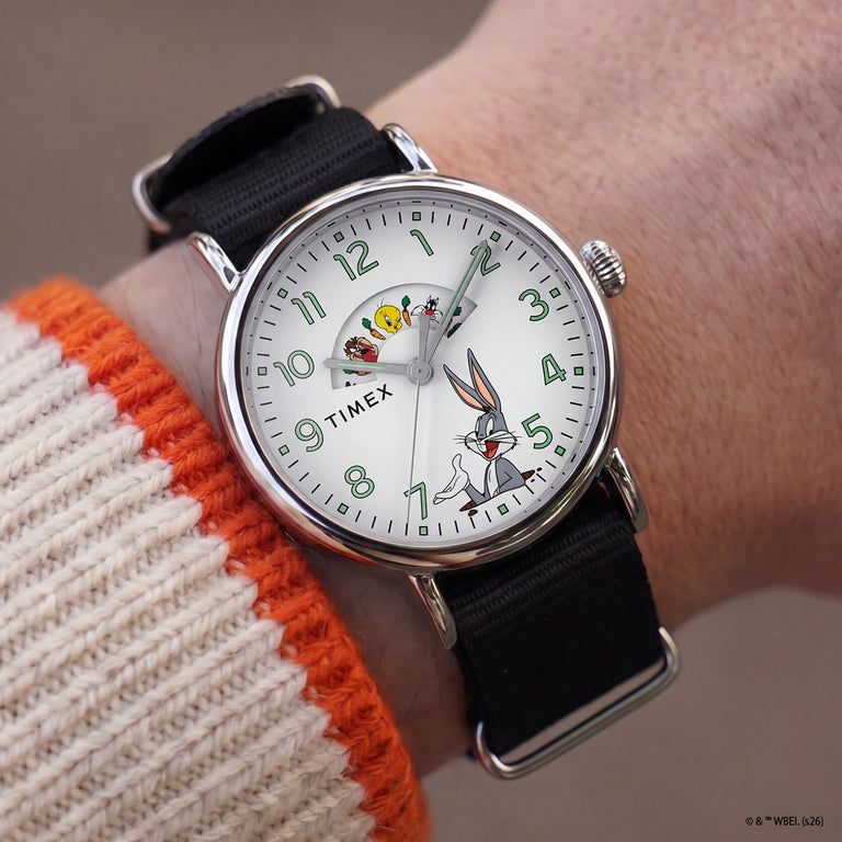 TW2Y99100 Looney Tunes Bugs and Friends x Timex Standard watch worn on a wrist, showing its white character dial, silver-tone case, and black fabric strap.
