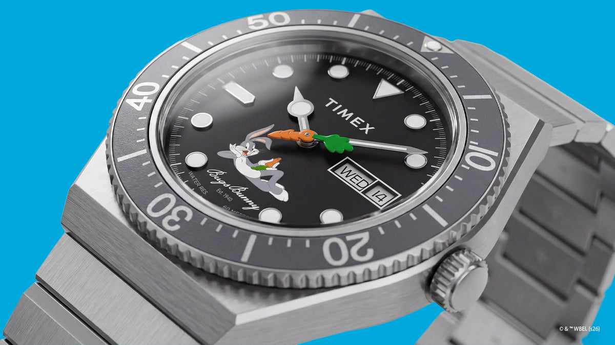 TW2Y99200 Angled close-up of the Bugs Bunny x Timex M79 watch featuring a black dial, carrot-shaped seconds hand, day-date window, and black bezel.