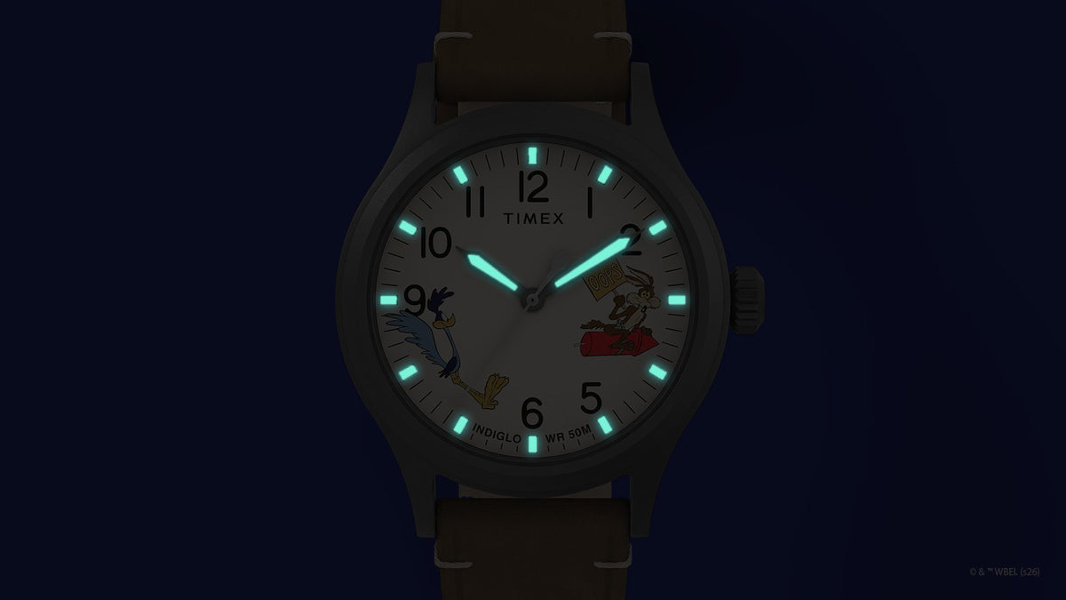 TW2Y99400 Reloj Road Runner & Wile E. Coyote x Timex Expedition® Scout con agujas y índices de color turquesa que brillan alrededor de la esfera con los personajes.