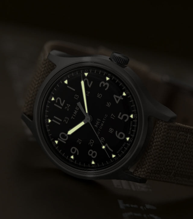 MK1® Automatic watch in low light, highlighting its glowing hands and hour markers.