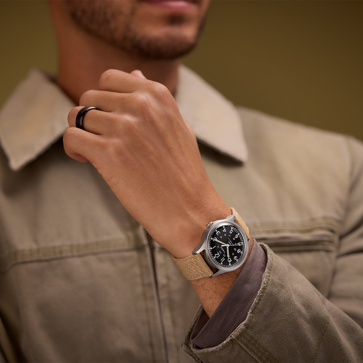 Person wearing the MK1® Automatic watch with a neutral-toned utility jacket.