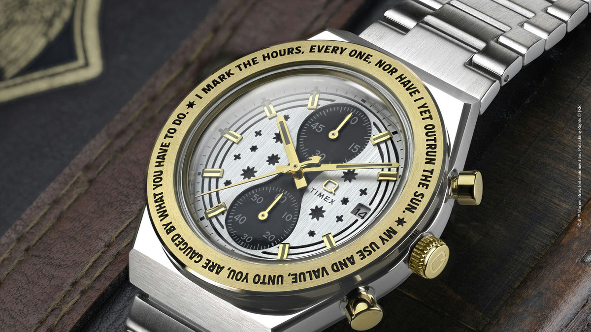 TW2Y75900 Close-up of the watch on a dark wooden surface, highlighting its gold-tone bezel, star-patterned dial, and silver-tone bracelet.