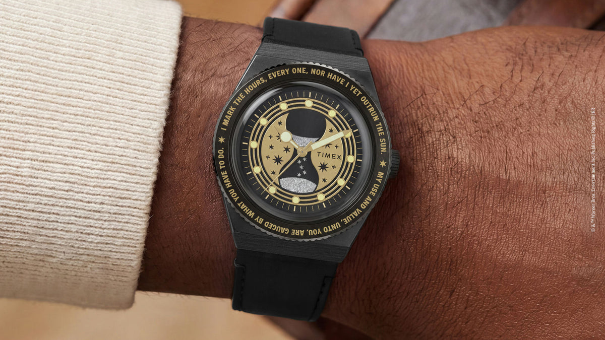 TW2Y76000 Harry Potter x Q Timex Time Turner watch worn on a wrist, with a black strap and gold hourglass design.