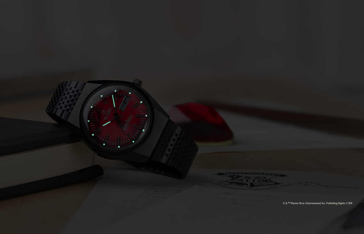 TW2Y99700 Harry Potter x Q Timex watch in low light, highlighting the glowing hands and hour markers on the red dial.