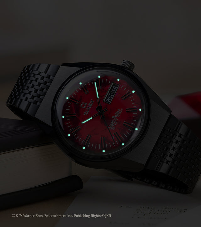 TW2Y99700 Harry Potter x Q Timex watch in low light, highlighting the glowing hands and hour markers on the red dial.