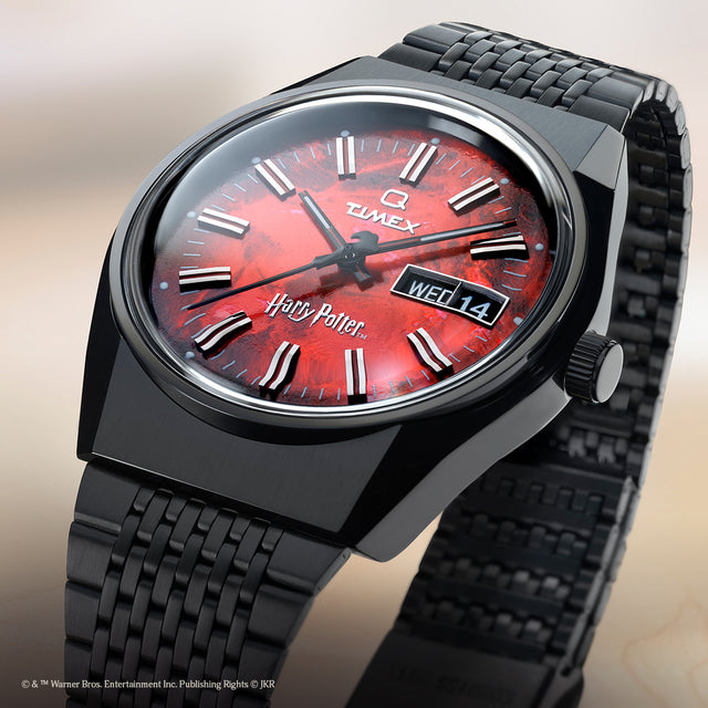 TW2Y99700 Close-up of the Harry Potter x Q Timex watch featuring a red textured dial, black case and bracelet, and day-date display.