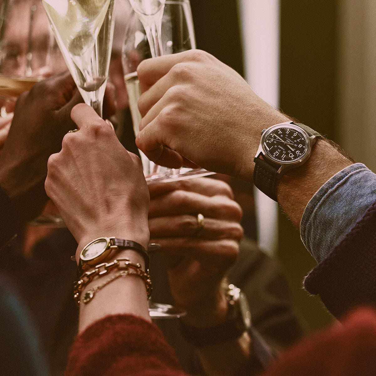 Unos amigos brindando con copas de champán, con relojes Timex visibles en dos muñecas.