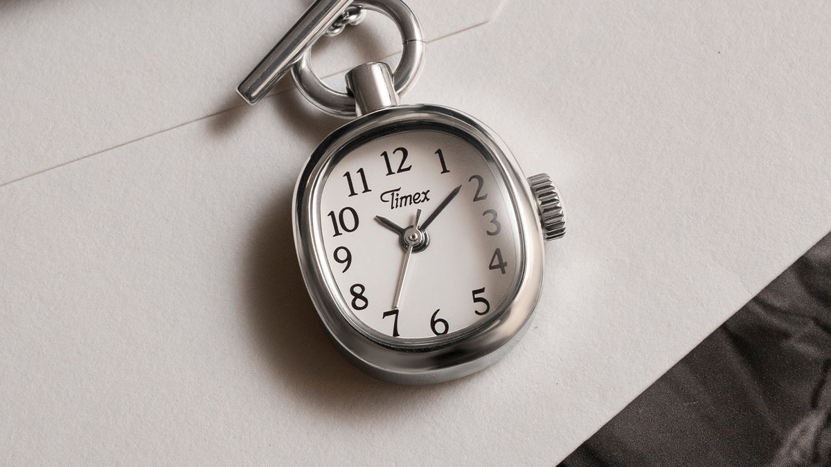 TW6A17600 Primer plano del colgante de reloj Cavatina® Mini con esfera blanca, números arábigos negros y caja de acero inoxidable pulido.