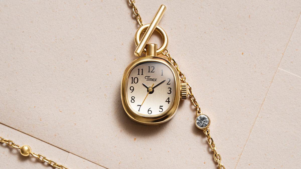 TW6A17700 Primer plano del colgante de reloj Cavatina® Mini, en el que se aprecian su caja en tono dorado, su esfera clara, sus números negros y su cierre de palanca.