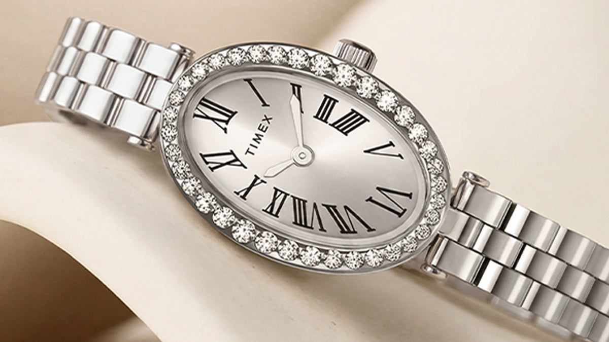 TW2Y90000 Primer plano de la esfera ovalada en tono plateado del reloj Timex Cavatina® Crystals, con números romanos negros, agujas en tono plateado y bisel con cristales.
