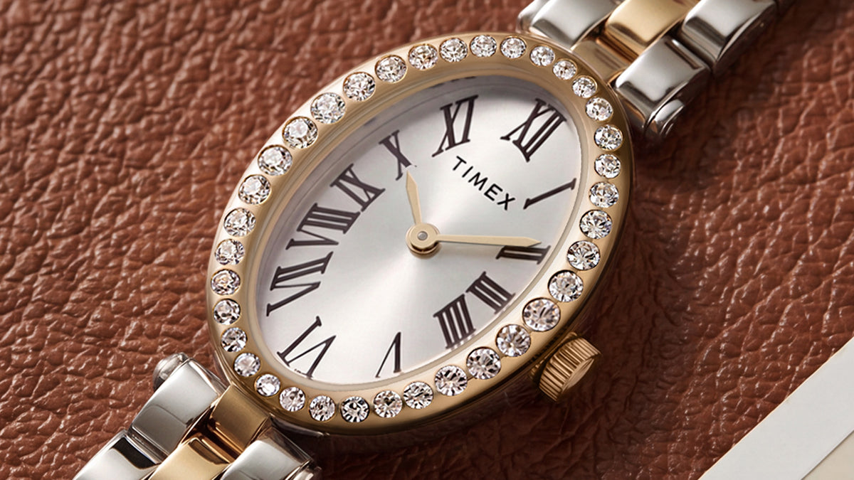 TW2Y90200 Primer plano de la esfera plateada del reloj Timex Cavatina® Crystals, con números romanos negros, agujas doradas y bisel ovalado adornado con cristales.