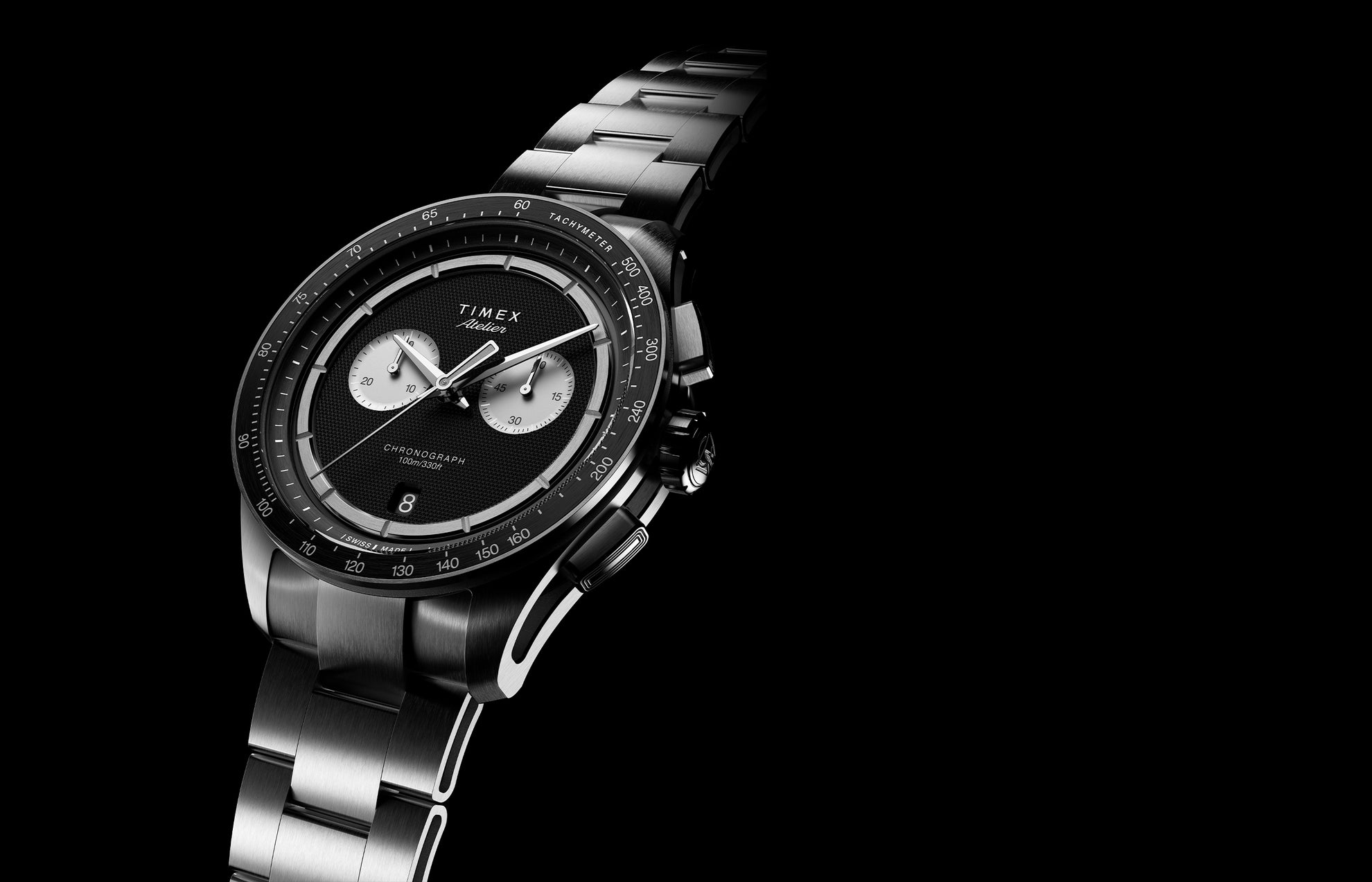 Timex Atelier Chronograph Quartz M1a watch with black textured dial, titanium case, and metal bracelet on black background