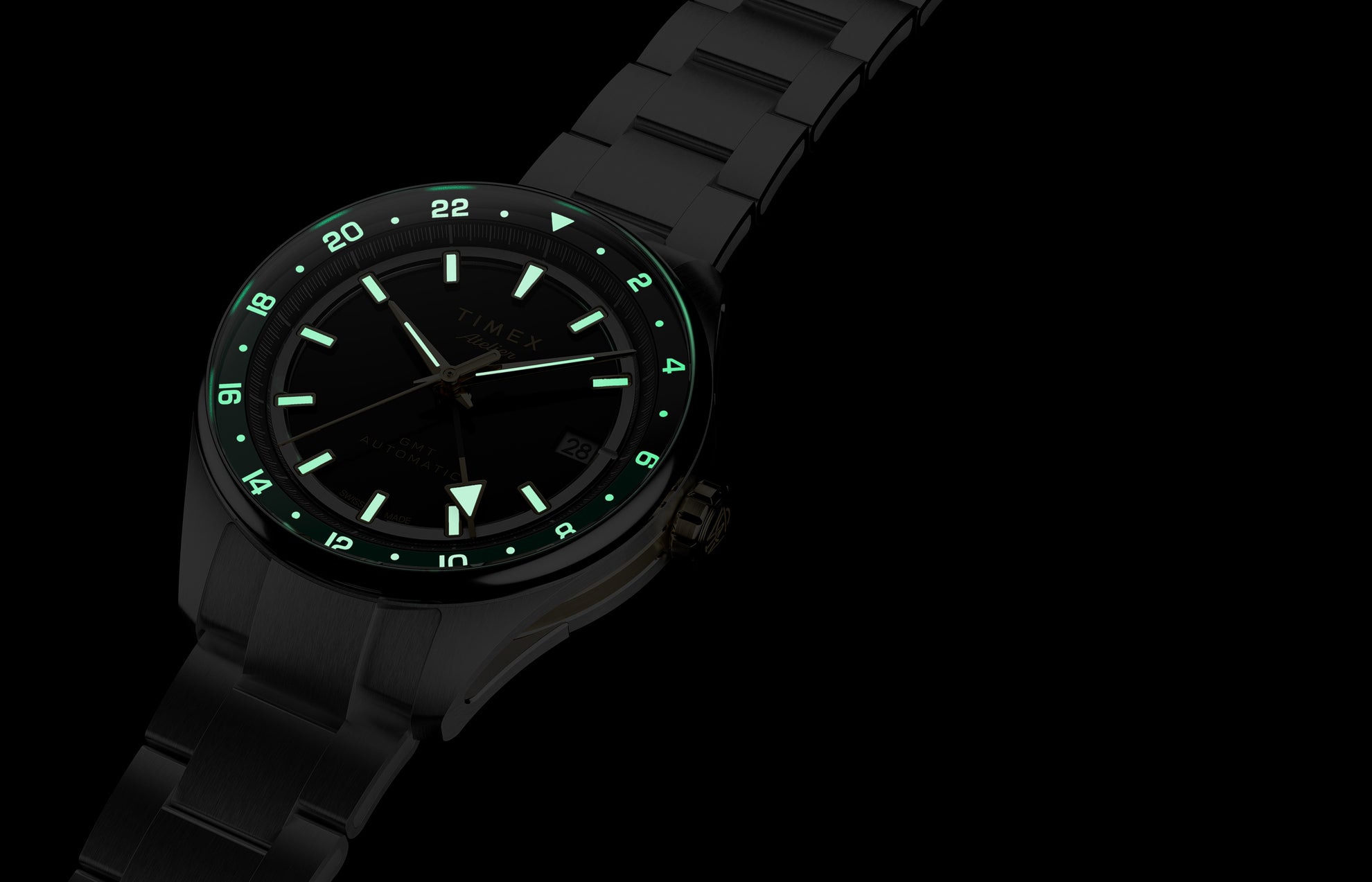Reloj Timex Atelier GMT Première M1a que brilla en la oscuridad, con índices horarios, agujas y escala de 24 horas iluminados.