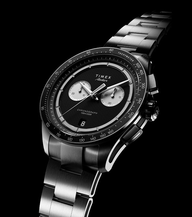 Timex Atelier Chronograph Quartz M1a watch with black textured dial, titanium case, and metal bracelet on black background