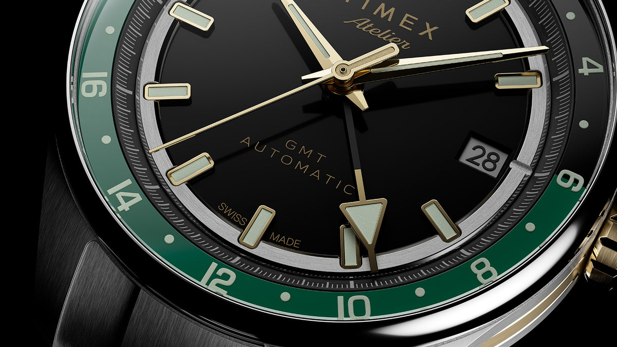 Primer plano detallado de la manecilla GMT, la ventana de la fecha, los índices luminosos y la escala verde de 24 horas.
