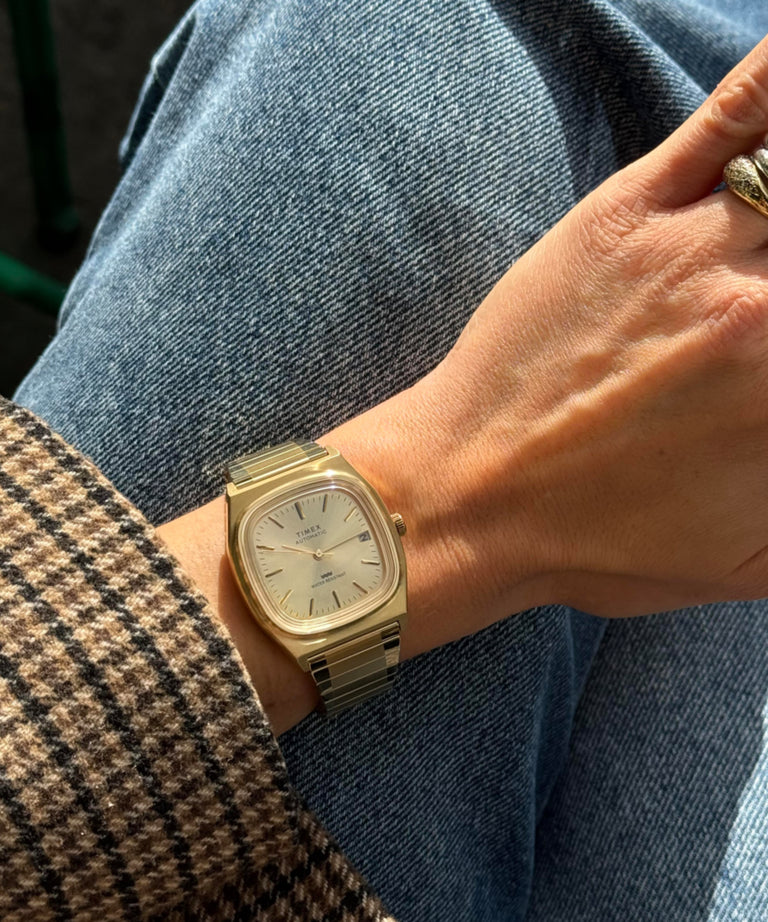 TW2Y07200 Reloj Timex® automático, reedición de la línea E de 1983, 34 mm, con correa extensible en tono dorado. Imagen principal de la muñeca.