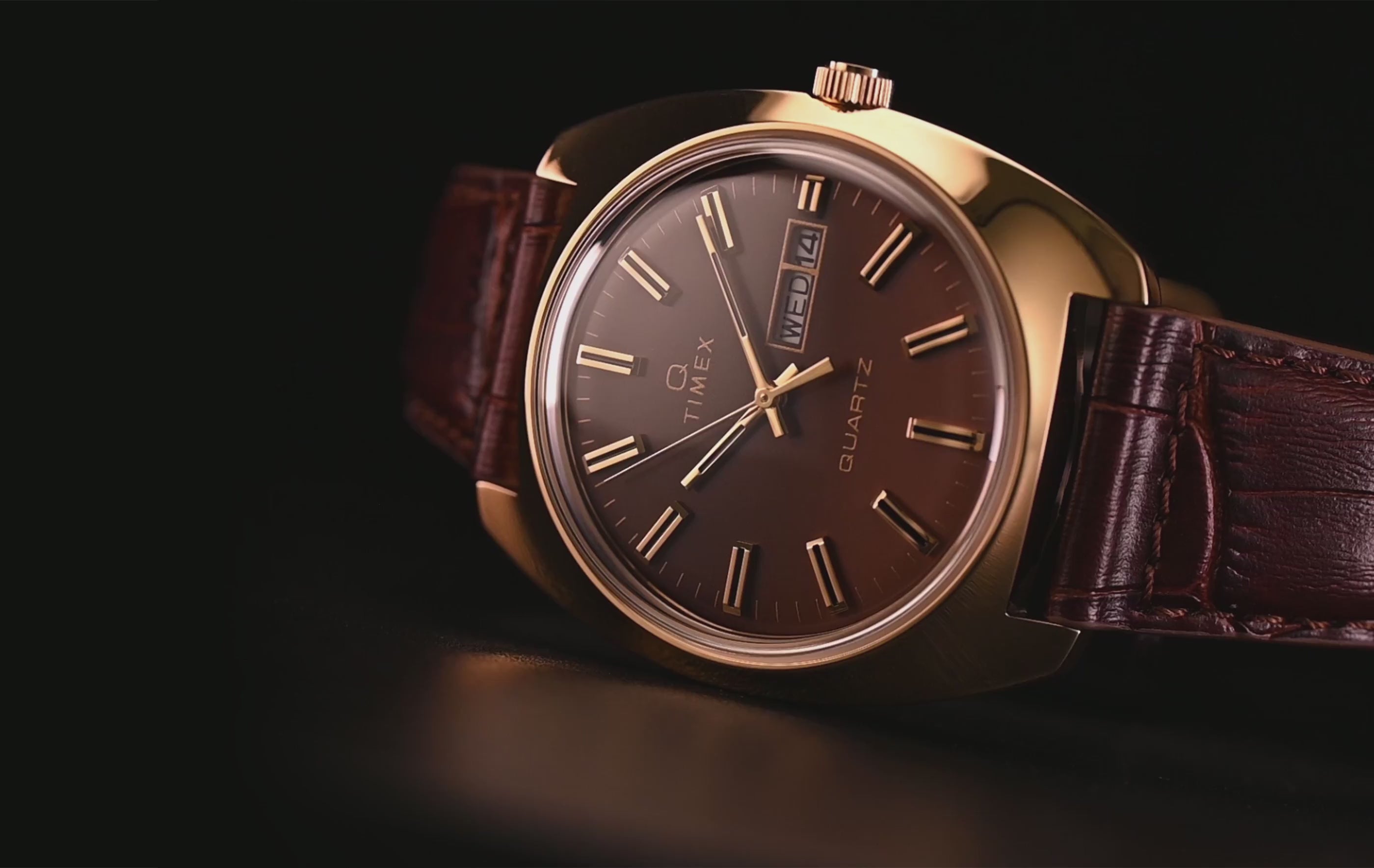 TW2Y87200 Gold-tone watch with a brown gradient dial, day-date display, and brown leather strap against a dark background.