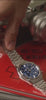 Video showcasing the Q Timex Falcon Eye Chronograph watch (model TW2W33700) rotating on a light gray surface. The footage highlights the brushed and polished stainless-steel case and bracelet, vibrant metallic blue dial with three chronograph subdials, applied hour markers, and date window.