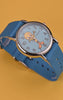 TW2Y99500 Rotating views of the Tweety Bird x Timex Weekender watch, highlighting its blue character dial, silver-tone case, and blue fabric strap against yellow and red backgrounds.