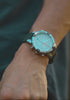 A rotating showcase video of the Timex Expedition Tide-Temp-Compass watch with a cream dial, stainless-steel case, and green silicone strap. The video highlights the compass bezel with cardinal direction markers, luminous hands and markers, orange tide indicators, and the date display at 6 o’clock.