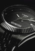 Dark, cinematic video showcasing the Timex x Wednesday Timex Legacy watch. The all-black timepiece is revealed through dramatic lighting, highlighting its textured dial with flying raven patterns, gothic “Wednesday” lettering, and a red skull date window.