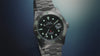 Promotional video featuring the Timex Deepwater Reef 200 Titanium dive watch. The watch is shown in close-up shots highlighting the black dial, aqua luminescent markers, titanium bracelet, rotating bezel, and screw-down crown. Water splashes around the watch, emphasizing its 200-meter water resistance. The lume glows vividly in dark conditions.