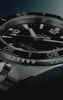 Promotional video showcasing the Timex Deepwater Arctic watch in close-up detail. The stainless steel dive watch with a black dial and rotating bezel appears against dark blue lighting, with rotating angles highlighting the bracelet, face, and textured bezel. Intercut underwater scenes show scuba divers swimming above coral reefs and schools of fish, reinforcing the watch’s ocean-inspired, professional diving aesthetic.