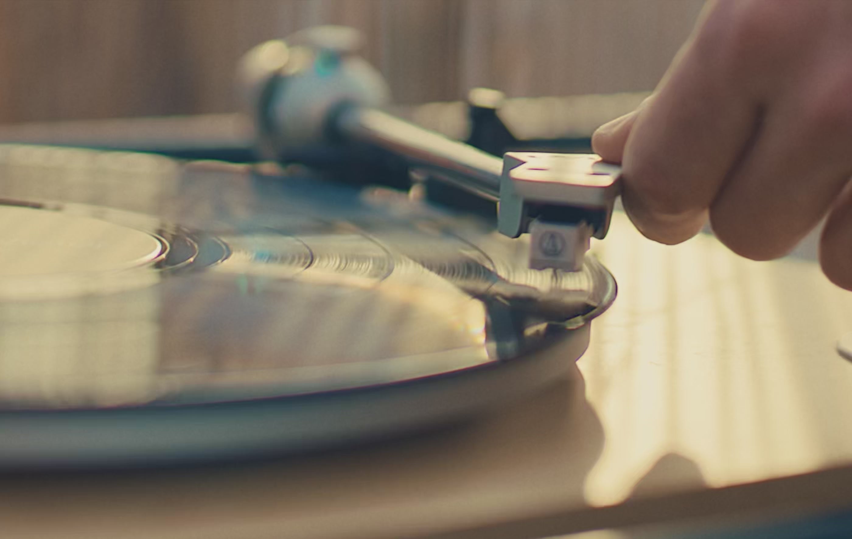 A warm holiday-themed montage featuring close-up shots of a spinning vinyl record, friends toasting drinks outdoors at dusk, and a detailed close-up of a Timex Waterbury chronograph watch glinting in soft light. The video ends with a nighttime sky and the message ‘Time is a Gift.