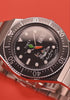 TW2Y99200 Rotating views of the Bugs Bunny x Timex M79 Automatic Signature Edition watch, highlighting its black character dial, carrot-shaped seconds hand, and silver-tone bracelet against red backgrounds.