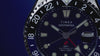 Scuba diver swimming above a colorful coral reef while wearing the Timex Deepwater Meridian 200 Automatic GMT, highlighting its dive-inspired design and 200-meter water resistance.
