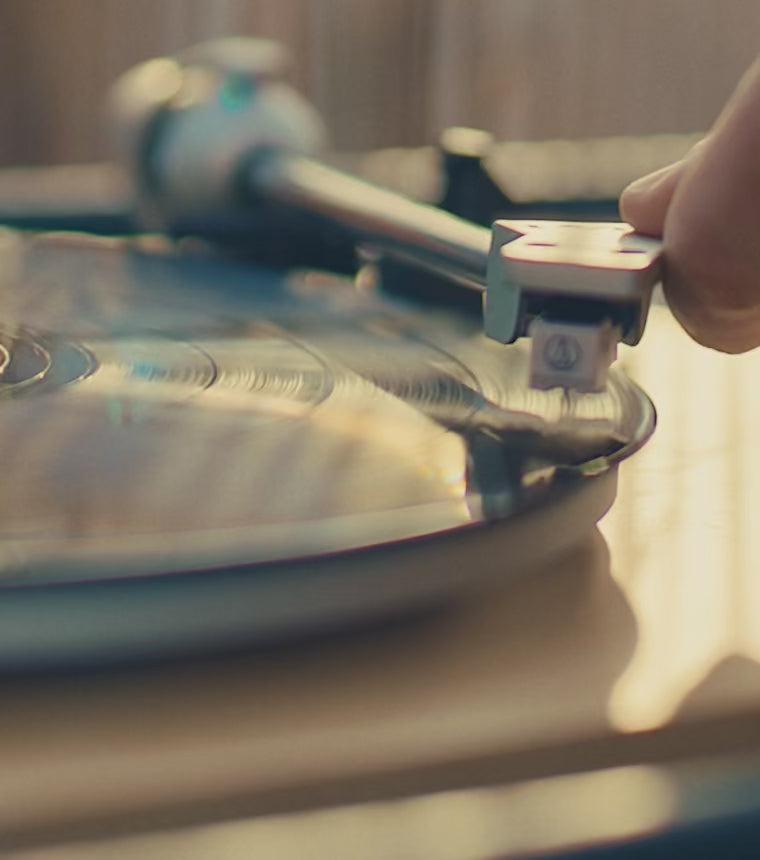 A warm holiday-themed montage featuring close-up shots of a spinning vinyl record, friends toasting drinks outdoors at dusk, and a detailed close-up of a Timex Waterbury chronograph watch glinting in soft light. The video ends with a nighttime sky and the message ‘Time is a Gift.